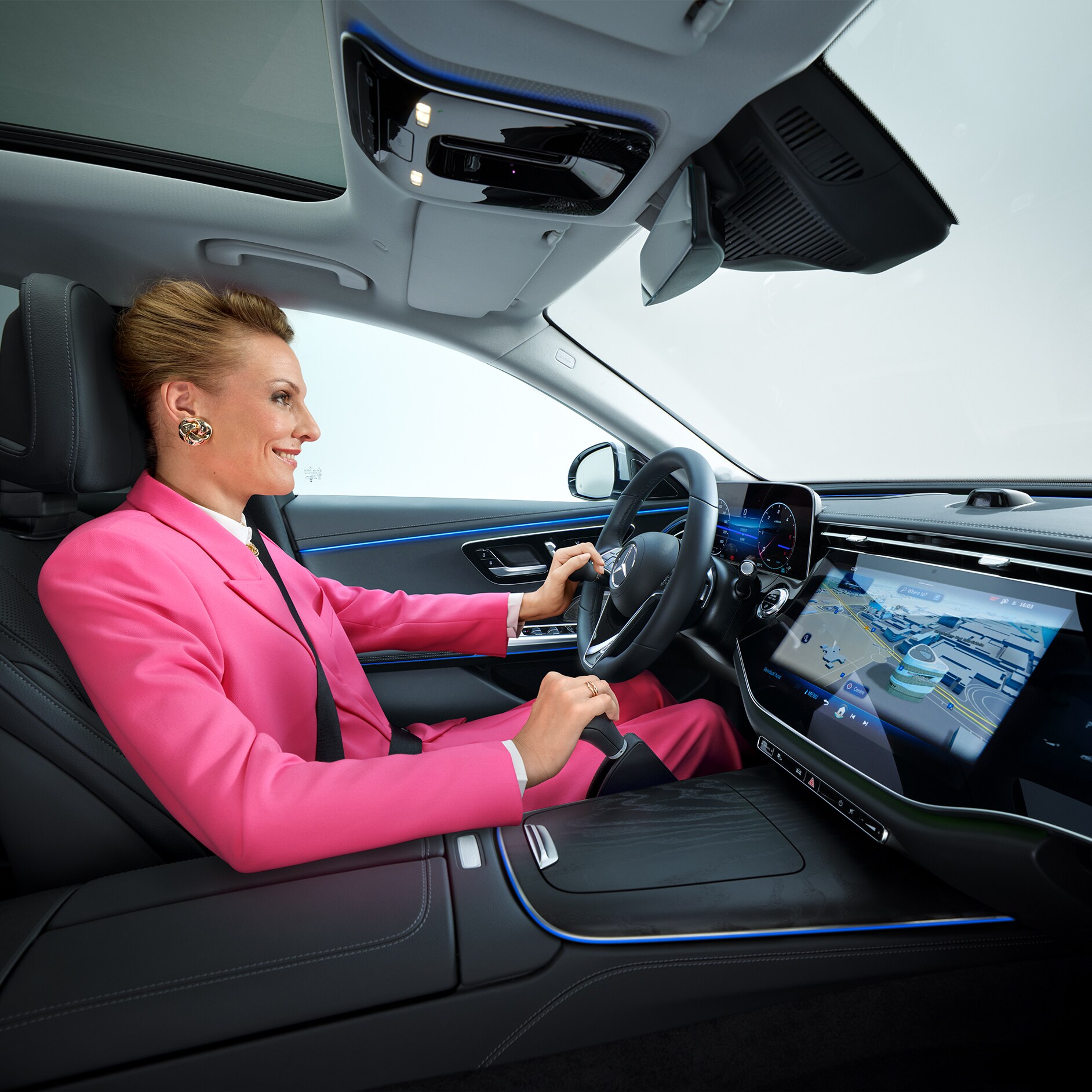 Průvodce „Více mobility“ | Pomůcky pro jízdu | Mercedes-Benz Pohled do interiéru vozidla Mercedes-Benz Třídy E přestavěného pro invalidy, ve kterém sedí za volantem žena používající madlo na volantu a zařízení pro ruční ovládání.