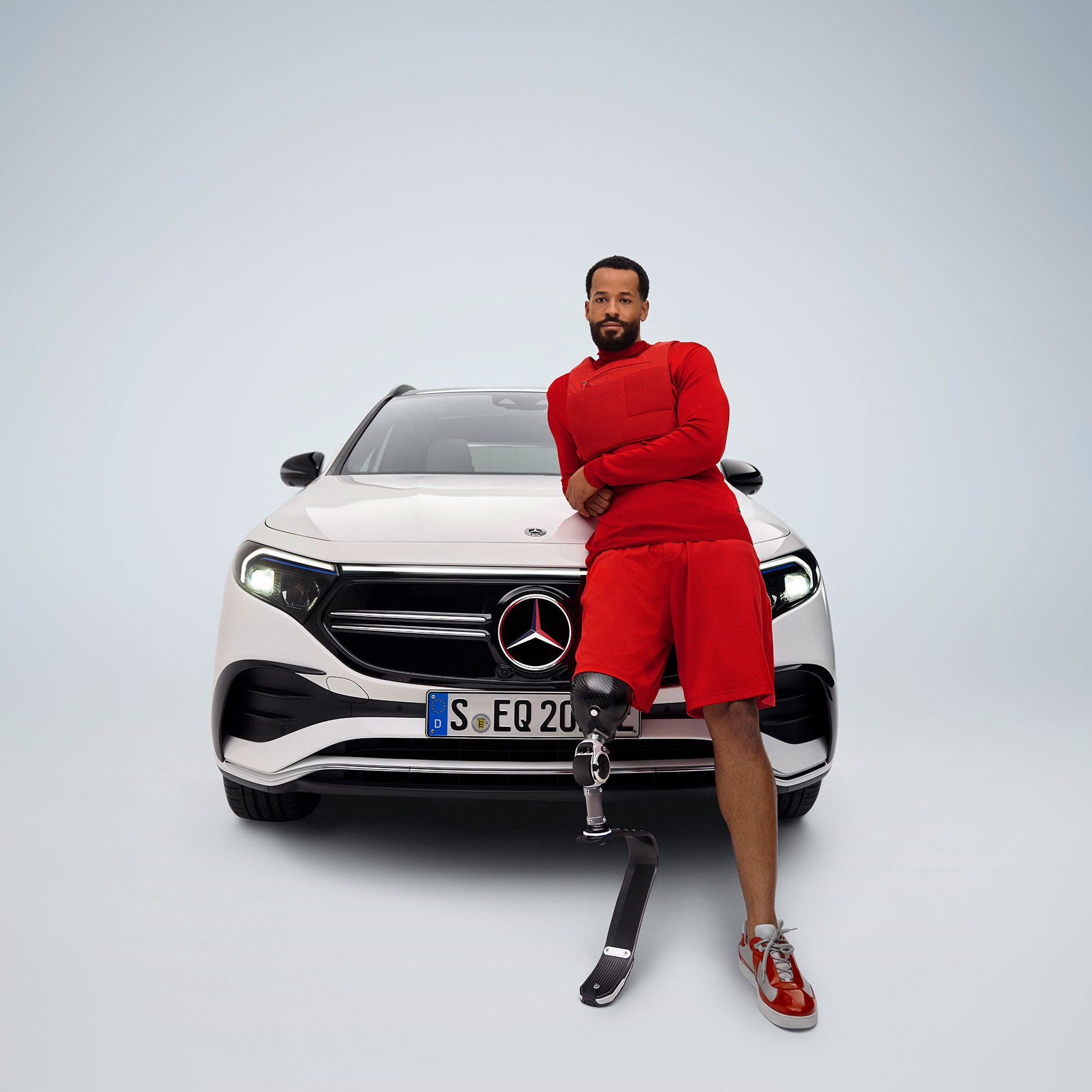 Prodloužení pedálů | Jízdní pomocné prostředky| Mercedes-Benz Čelní pohled na Mercedes-Benz EQA, který byl upraven pro bezbariérový přístup, a muž s protetickou nohou.