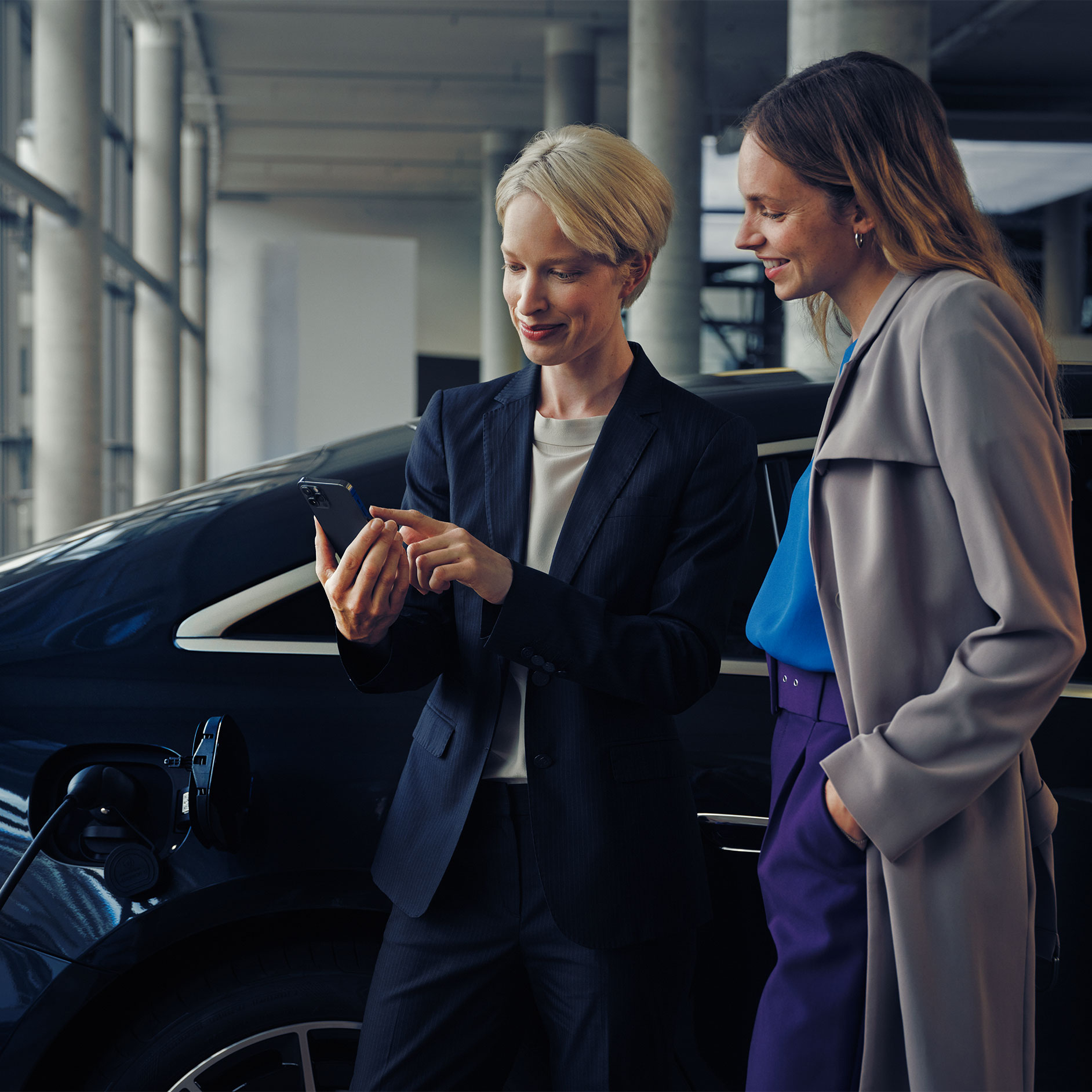 Poradenství při instalaci wallboxu | Nabíjení | Mercedes-Benz Dvě ženy před nabíjejícím se sedanem EQE.